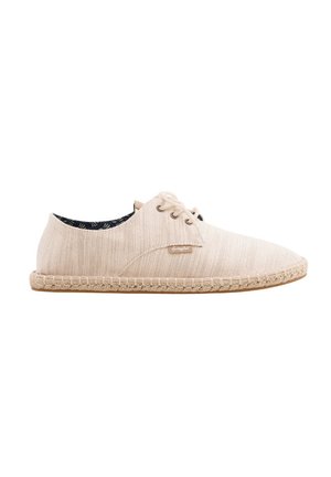 Beige Stoff-Espadrille mit Schnürung, geflochtener Sohle und dunklem gemustertem Innenfutter, von der Außenseite gesehen.
