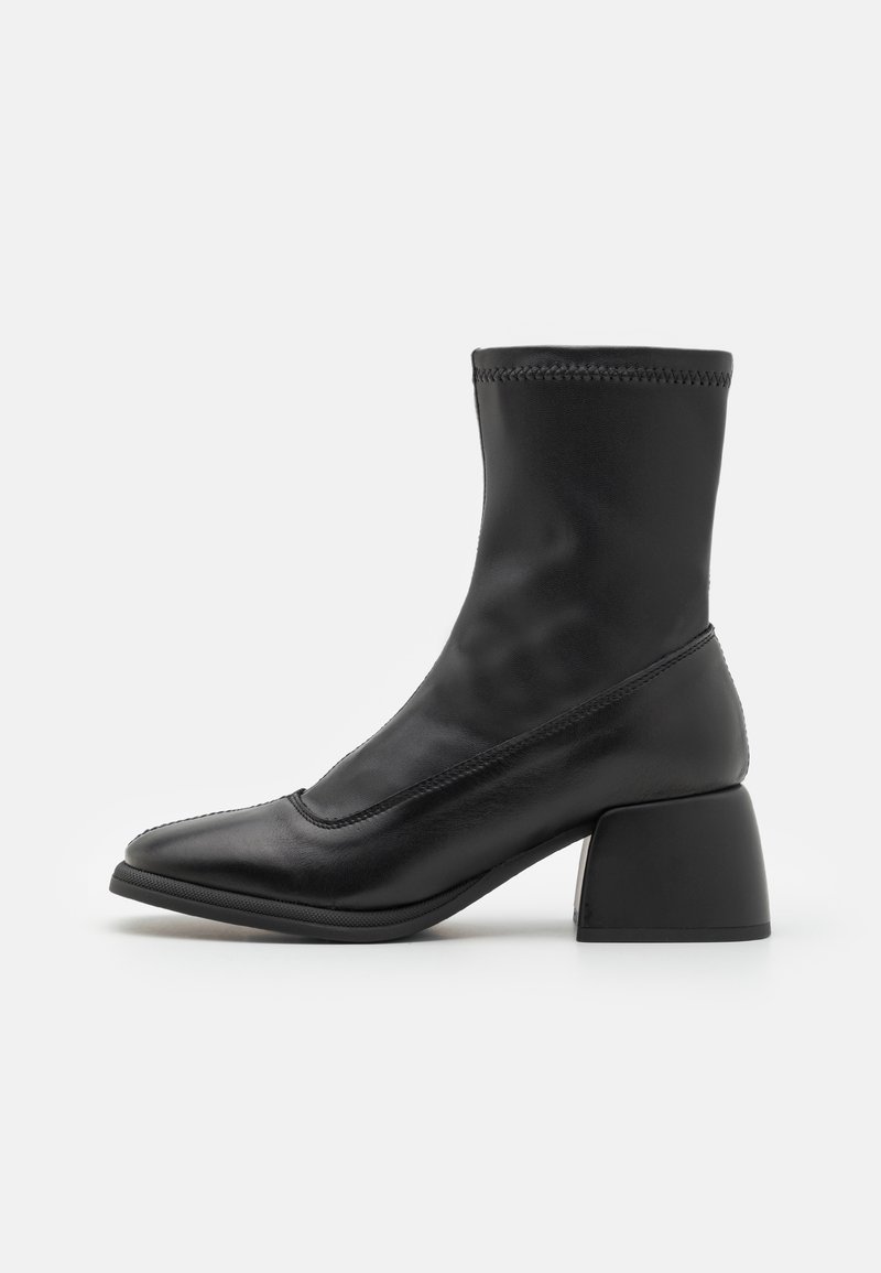 Bottines noires en cuir lisse avec un bout arrondi et un talon bloc, dotées d'une tige ajustée semblable à une chaussette et de détails de couture subtils.