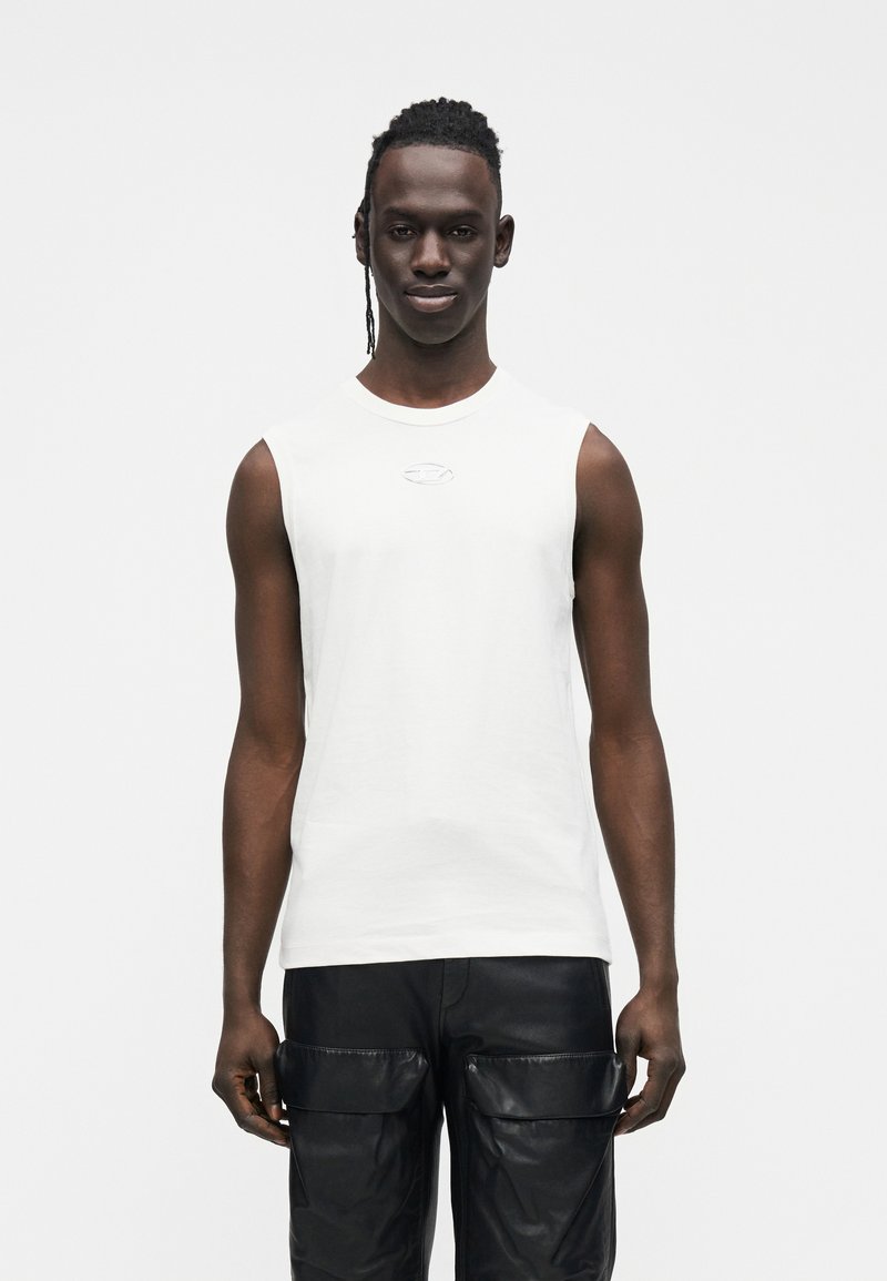 Witte katoenen mouwloze T-shirt met een subtiel logodetail, gecombineerd met zwarte leren cargobroek met meerdere zakken en een gladde textuur.