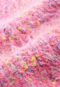 Soe roosa kangas tekstuurse pinnaga, millel on mitmevärvilised täpid sinise, kollase ja rohelise värvusega, luues elava mustri.