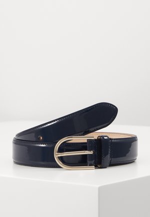 Ceinture en cuir bleu foncé brillant enroulée sur une surface blanche avec une boucle métallique dorée arrondie et des coutures le long des bords.