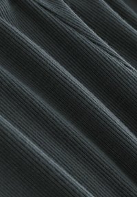 Mörk ribbad tyg med en mjuk textur, som visar horisontella linjer och försiktiga vågor, lämplig för kläder eller möbeltyg.