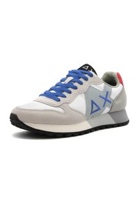 Scarpa sportiva grigia e bianca con lacci blu, realizzata in materiale scamosciato e sintetico, design a metà caviglia e suola in gomma nera texturizzata.