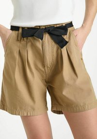 Shorts en coton khaki avec une ceinture en tissu noir. Présentent des plis et des poches. Texture lisse et design jusqu'aux genoux.