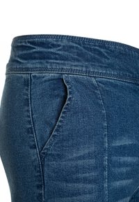 Tmavě modré džíny z denimu s hladkou texturou, bočními kapsami a páskem s prošívaným zakončením.