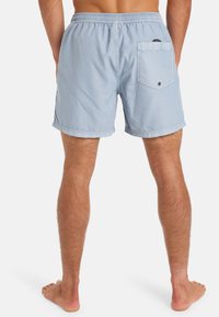 Světle modré plavecké šortky vyrobené z měkké, lehké tkaniny, s elastickým pasem a zadní kapsou na knoflík.