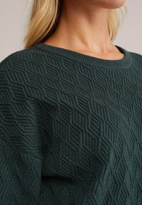 Pull en laine vert tricoté avec un motif en nid d'abeille texturé, doté d'un col rond côtelé et d'un tissu doux et épais.