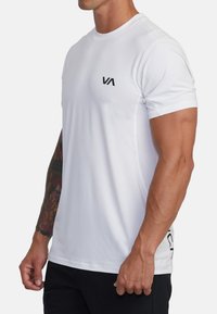 Witte sport t-shirt met korte mouwen, ronde halslijn en zwart logo op de borst; heeft een gestructureerde zijpaneel voor ademend vermogen.