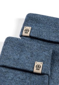 Two folded blue knitted beanies with a beige fabric tag featuring a circular logo are displayed on a white background.