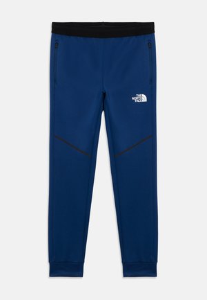 Pantaloni sportivi blu navy con fascia in vita nera, dotati di tasche laterali con zip e dettagli neri lungo la parte inferiore della gamba. Logo sull'anca.