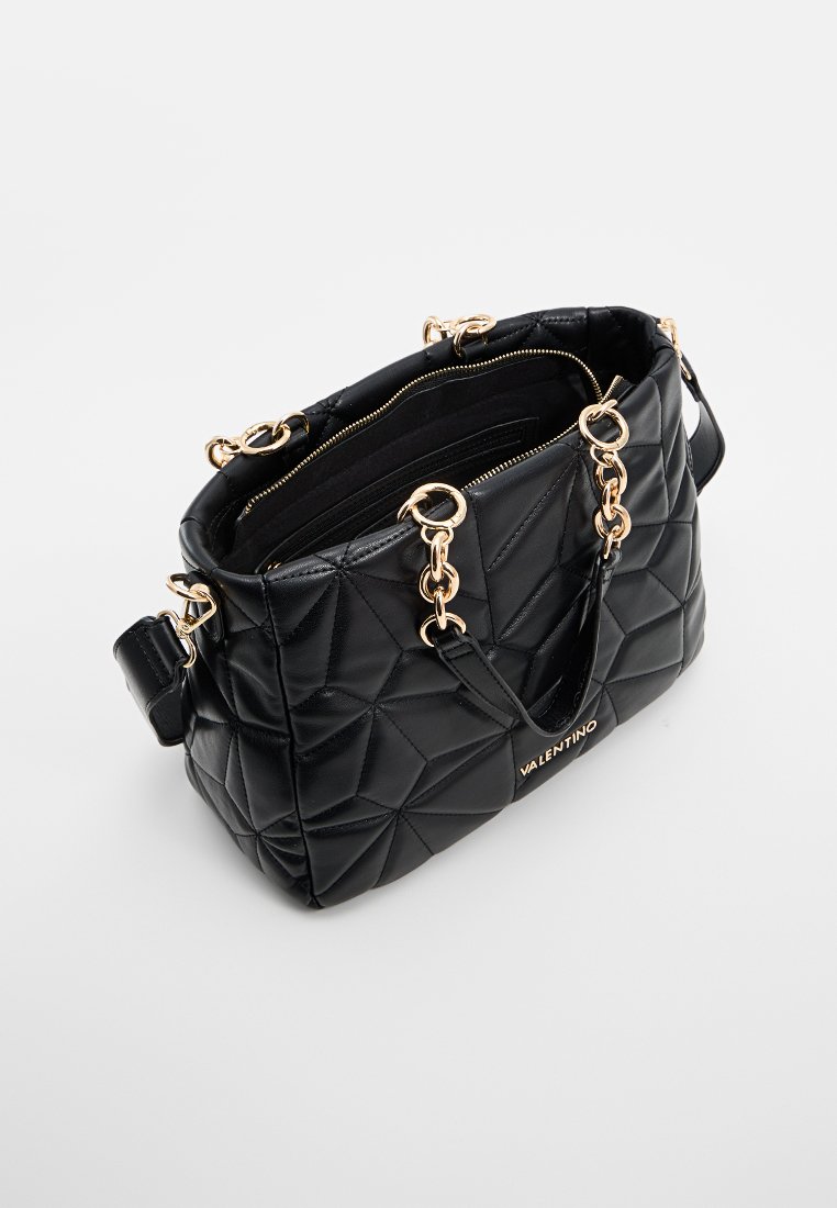 Sac à main en cuir matelassé noir avec des accents en chaîne dorée, fermeture éclair, poignées doubles et détail du logo de la marque à l'avant.