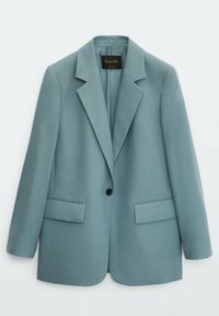 Veste ajustée bleu clair à un bouton, avec revers crantés et poches à rabat sur le devant, suspendue devant un fond blanc.