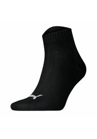 Schwarze Knöchelsocke aus glattem, dehnbarem Stoff, mit einem gerippten Bündchen und einem kleinen, gestickten weißen Logo an der Seite.