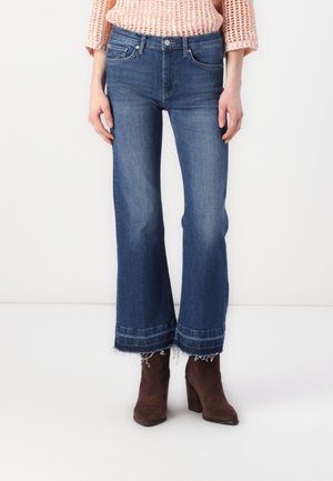 Bredde ben blå jeans med slitt hem, beltehemper og frontlommer. Laget av denimstoff med en litt falmet finish.