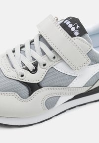 Sneaker grigio con tomaia in pelle e mesh, dettagli bianchi e neri a contrasto, chiusura con lacci e strap in velcro. Suola in gomma.