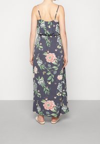 Blommig maxiklänning med justerbara spaghettiband; har en marinblå bakgrund, stora rosa och gröna blommor, elastisk midja och en svängig silhuett.