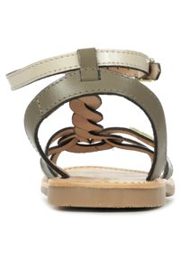 Sandalettes plates marron avec des brides en cuir vert olive et une sangle de cheville couleur crème. Présente des détails tressés et une semelle intérieure texturée.