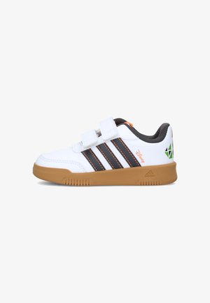 Zapatilla blanca para niños con suela marrón, rayas negras, tiras de velcro y logotipos verdes y naranjas de Disney y Adidas.