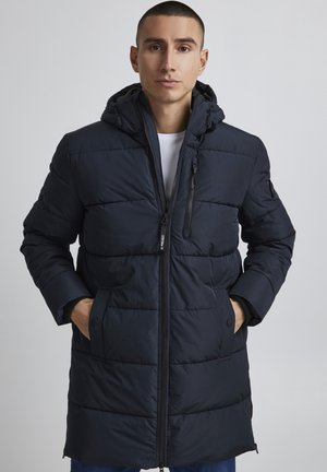 Navy puffer coat with a hood, zippered front, and side pockets. Features quilted design and elastic cuffs for warmth. Smooth texture.