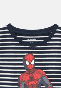 Námornícka a biela pásikavá košeľa s červenou a šedou grafikou Spider-Mana na prednej strane, okrúhly výstrih a etiketa "name it" vo vnútri goliera.