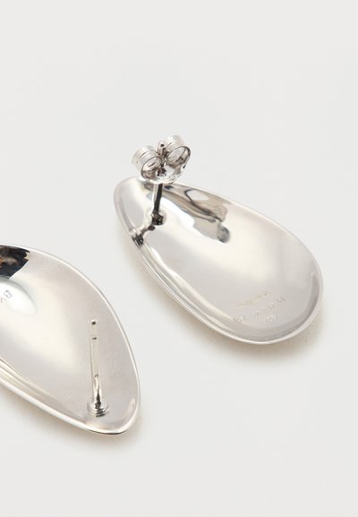Két polírozott ezüst, ovális alakú, fülbevaló pillangós zárral fehér felületen.