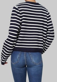 Pull en rayures bleu marine et blanches avec un col rond et un ourlet côtelé, associé à un jean en denim bleu moyen avec un design classique à cinq poches.