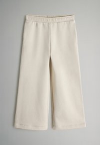 Pantalones de pierna ancha en color beige, hechos de una tela suave con una cinturilla elástica. Bordes dobladillos sin patrones visibles ni herrajes. Textura lisa.