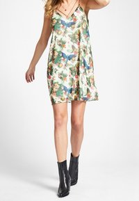 Kleid mit Blumenmuster aus leichtem Stoff, mit V-Ausschnitt, schmalen Trägern und lockerer Passform. Kombiniert mit schwarzen Stiefeletten.