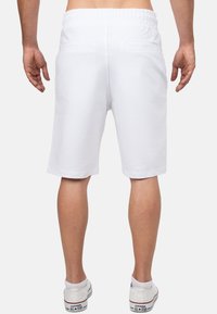 Witte katoenen shorts met een elastische tailleband, voorzien van twee achterzakken en een relaxte pasvorm, eindigend net boven de knie.
