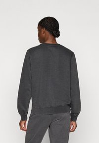 Tumehall sweatshirts pikkade varrukatega, soonikuga mansetid ja alläär. Omab logo taga krae juures ning pehmet, tekstuurset kangast.