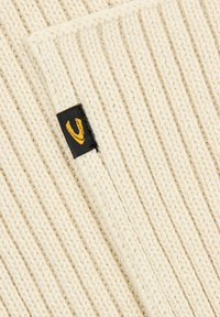 Beige strikket stof med lodrette ribber. Har et sort mærke med en gul logoaccents. Blødt, varmt materiale.