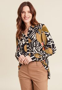 Chemise à manches longues avec boutons, présentant un imprimé abstrait noir et blanc agrémenté d'accents verts, rouges et jaunes. Tissu doux avec une coupe décontractée.