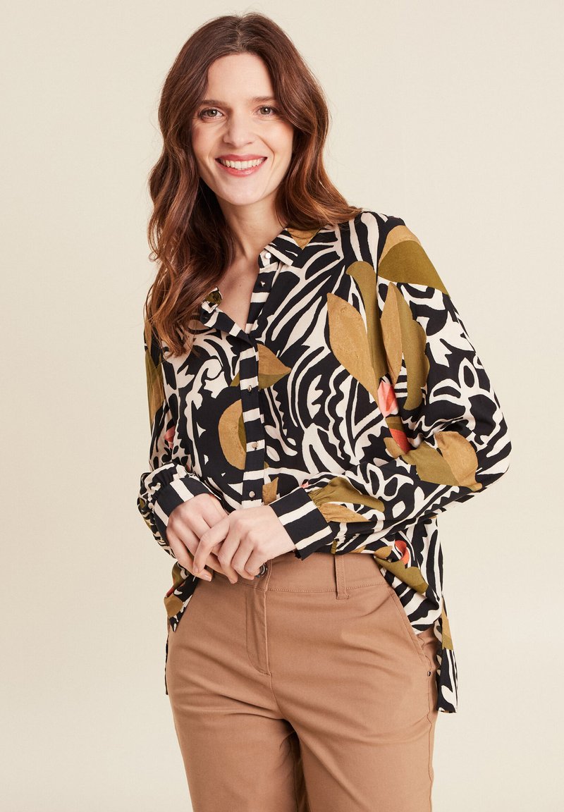 Chemise à manches longues avec boutons, présentant un imprimé abstrait noir et blanc agrémenté d'accents verts, rouges et jaunes. Tissu doux avec une coupe décontractée.