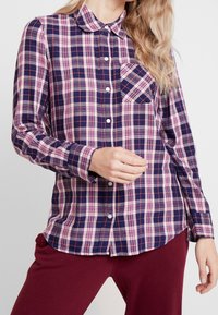 Marinblå och rosa rutig skjorta med knapp, kavajliknande hals och bröstficka, med långa ärmar och klassisk passform.