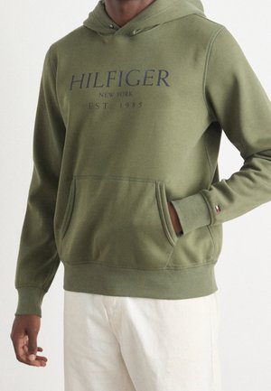 Oliwkowa bluza z kapturem z kieszenią z przodu, z granatowym napisem "HILFIGER NEW YORK EST 1985" na piersi oraz małym akcentem logo na rękawie.