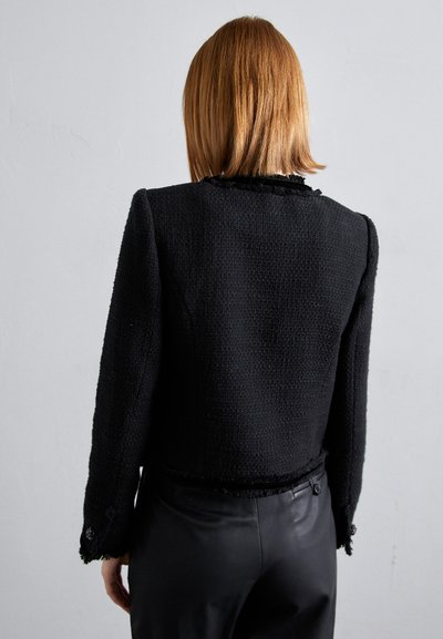 Zwart tweed jasje met een cropped ontwerp, geweven stof, franjes aan de randen en decoratieve knopen bij de manchet en taille.