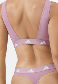 Rosa sport-bh och matchande trosa, tillverkad av mjukt tyg. Har breda axelband och logodetaljer i vitt längs bandet.