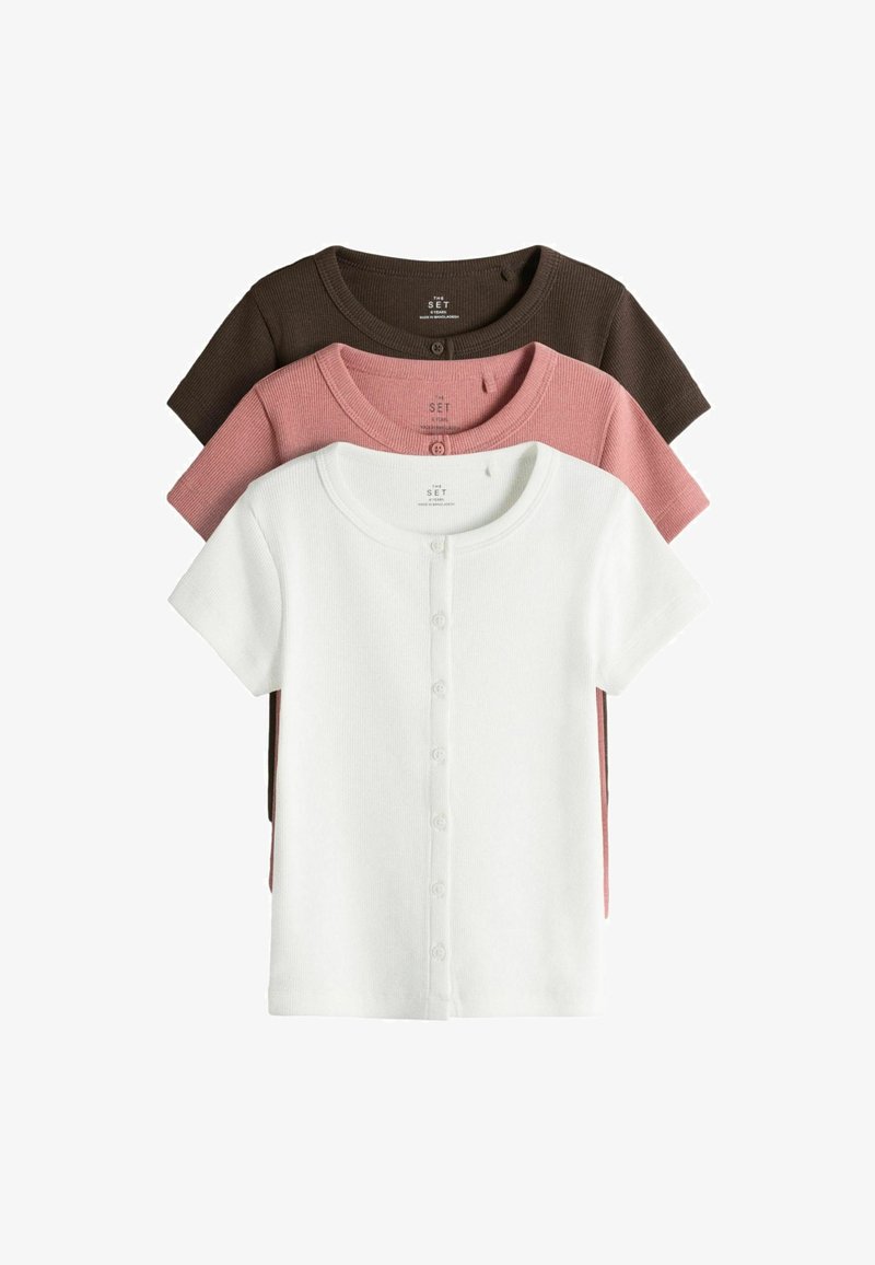 Drie korte mouw ribgebreide button-up tops in wit, roze en donkerbruin, gestapeld met wit bovenop.