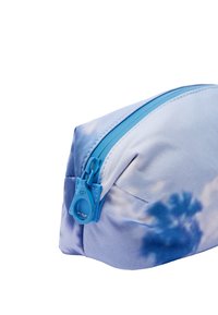 Niebieska torba w wzory o zaokrąglonym kształcie. Materiał wydaje się miękki i przypomina tkaninę. Posiada niebieski zamek błyskawiczny oraz subtelny wzór chmur na powierzchni.