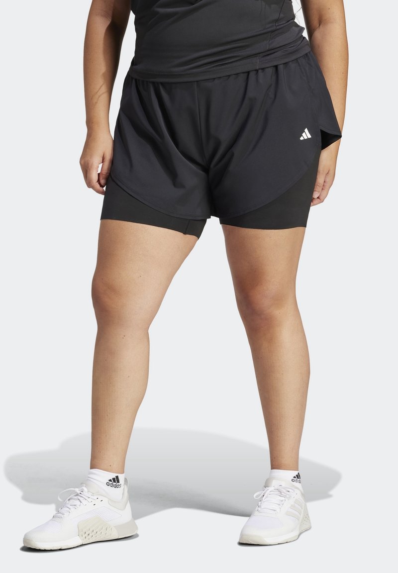 Černé sportovní šortky s překrývající se vnější vrstvou přes přiléhavé černé vnitřní šortky, vyrobené z lehké látky. Viditelné bílé logo Adidas.