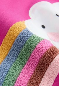 Bunt gemusterter Plüschstoff mit einem Bärenmotiv, der strukturierte Streifen in Gelb, Blau, Grün, Pink und Braun auf einem pinken Hintergrund zeigt.