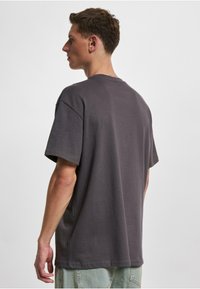 Grå bomull t-skjorte med avslappet passform, korte ermer, senkede skuldre og rund hals; glatt tekstur og minimalistisk design.