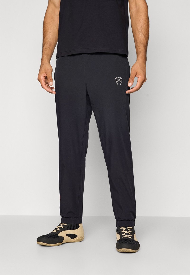 Black athletic pants with a slim fit, featuring a minimalist design and an embroidered logo. Made of smooth, lightweight material with elastic cuffs.