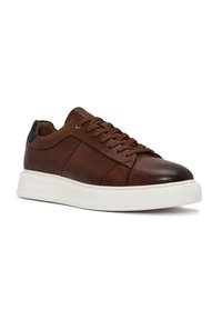 Sneaker in pelle marrone con finitura liscia, pannello laterale texturizzato, suola bianca piatta e accento del tallone nero a contrasto. Design con lacci sul davanti.