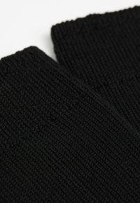 Guanti a maglia neri con texture a coste, con una vista ravvicinata che mette in evidenza il motivo intrecciato e il tessuto morbido. Nessun hardware o accento visibile.