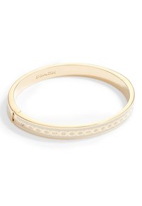 Gold-tone bangle bracelet with cut-out circle pattern, smooth finish, and small clear gemstones. Closure mechanism on one side.
