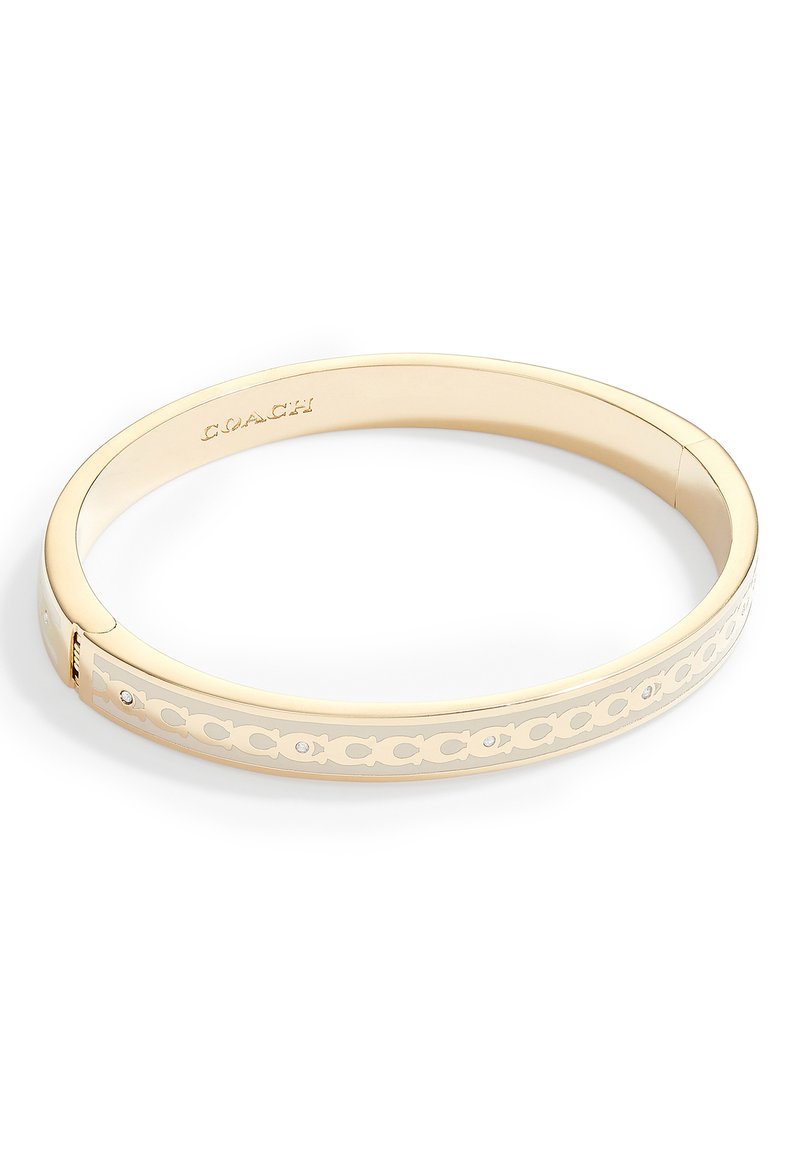 Gold-tone bangle bracelet with cut-out circle pattern, smooth finish, and small clear gemstones. Closure mechanism on one side.