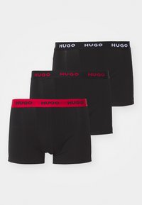 Drei Paar schwarze Boxershorts mit HUGO-Logos; eines hat einen roten Bund, die anderen haben schwarze und weiße Bünde. Weicher Stoff.