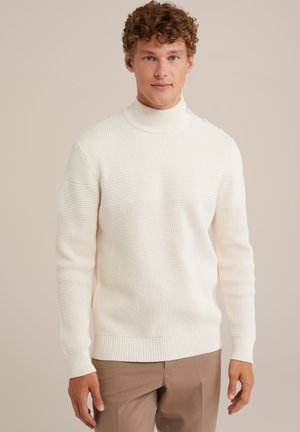 Bela pletena pričeska s turtleneck ovratnikom in teksturiranim vzorcem, ki vsebuje vodoravne črte in gumb na rami.