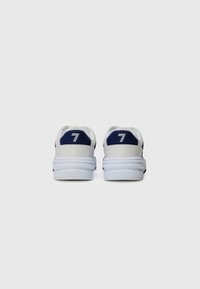 Adidași albi și bleumarin cu un material texturat pe partea superioară, guler căptușit, tocul înălțat și un logo proeminent cu numărul 7 în spate.
